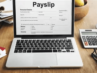 Payslip displayed on a laptop with calculator on desk